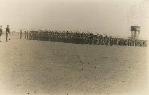 Large Group of Soldiers with Rifles Near Water Tower